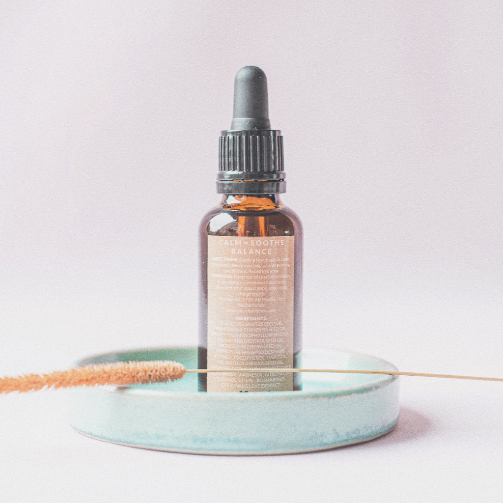 Facial oil Neroli bottle on a turquoise plate with a piece of dry flower