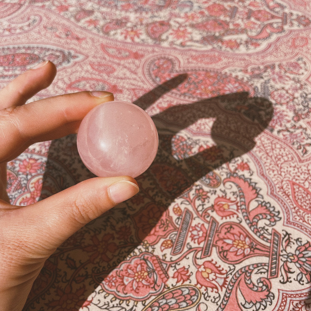 1 rose quartz ball of Akasha blends in hand on a nice pattern background