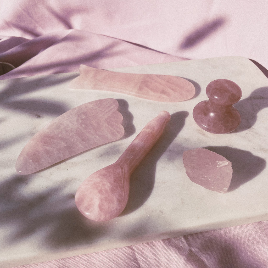 Collection of Akasha blends Rose Quartz tools including one Rose Quartz Spoon on pink background